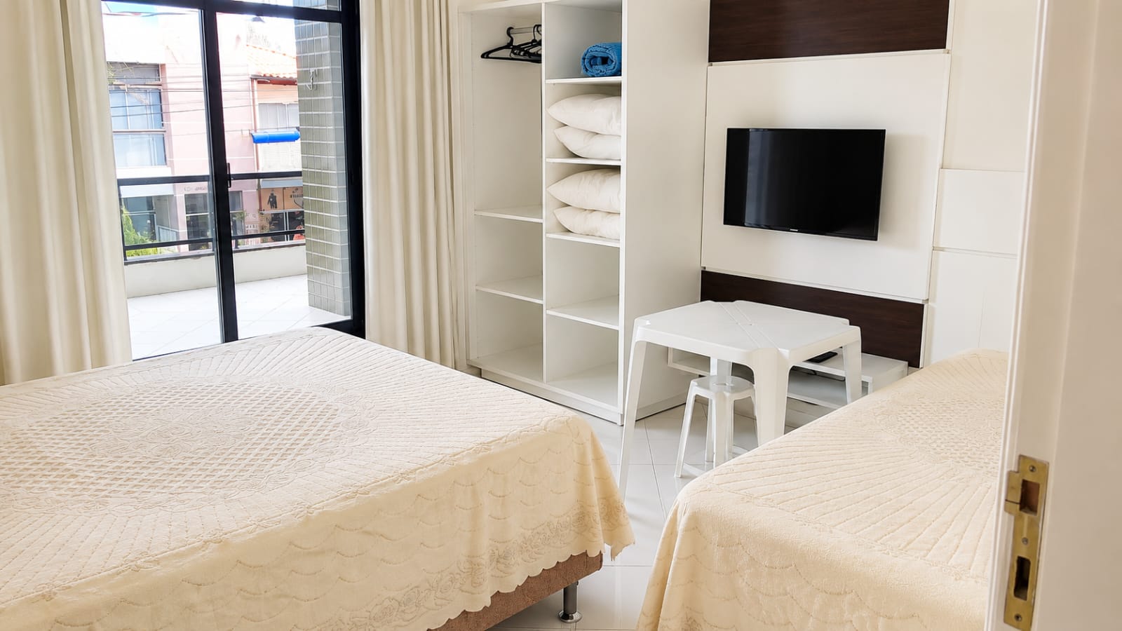 Quarto com cama de casal, cama auxiliar e TV
